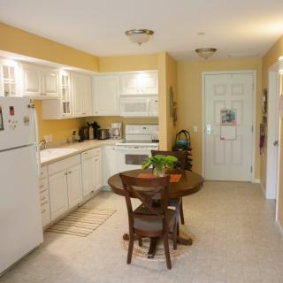 A cozy kitchen with white cabinets, yellow walls, and a round dining table.