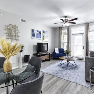 A modern living room with stylish furnishings, including a TV, circular coffee table, and decorative wall art.