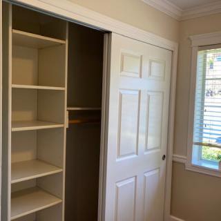 An interior view of a room featuring a closet with built-in shelves and a window.