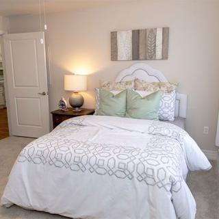 A well-decorated bedroom featuring a neatly made bed with patterned bedding, soft pillows, and a bedside lamp.