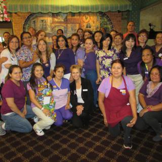 A group of people posing together indoors, many wearing casual clothing and smiling.