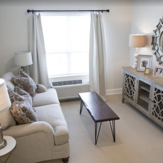 A cozy and well-lit living room with a sofa, coffee table, and decorative mirror.