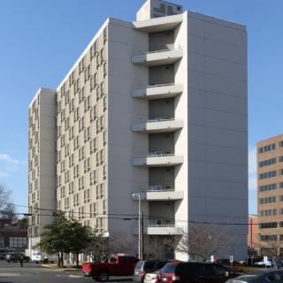 A high-rise apartment building in an urban area under a clear blue sky.