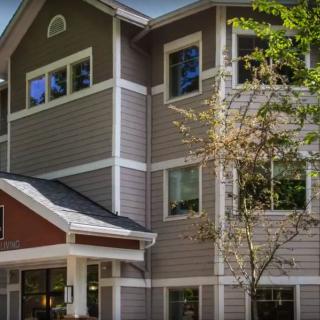 A residential building with multiple windows, surrounded by trees.