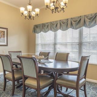 A well-decorated dining room featuring a large table, several chairs, and an elegant chandelier.