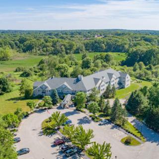 Aerial view of a building surrounded by lush greenery and a parking lot on a sunny day.