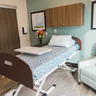 A well-designed patient room featuring a hospital bed and a comfortable seating area.