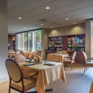 A cozy restaurant interior with dining tables and a small library section.