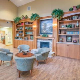 A cozy lobby with a fireplace, surrounded by bookshelves and comfortable seating.