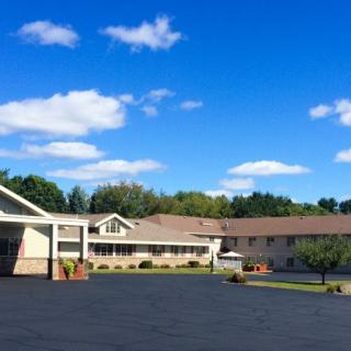 A motel with a large parking lot under a clear blue sky with a few clouds.