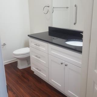 A modern bathroom with white cabinets and a granite countertop.