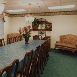 A formal dining room with a long table set for a meeting or meal, featuring elegant chairs and floral decorations.
