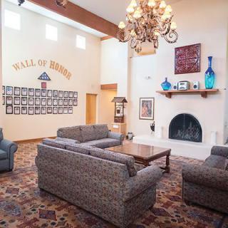 A cozy lobby with a seating area, chandelier, and decorated fireplace.