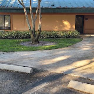 A peaceful pathway leading to a well-maintained building surrounded by greenery.