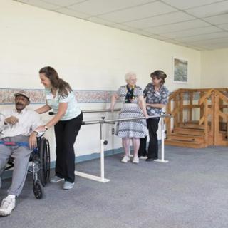 Caretakers assisting elderly individuals in a rehabilitation setting.
