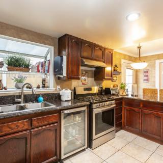 A modern kitchen with dark wooden cabinets, stainless steel appliances, and a tiled floor.