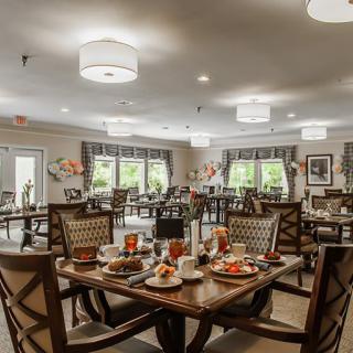 An elegantly decorated dining room with neatly arranged tables and chairs, bathed in natural light.