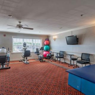 A fitness room equipped with stationary bikes, exercise balls, and a television.