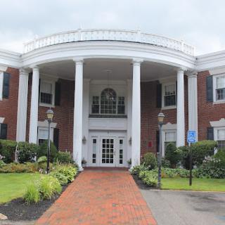A beautifully designed colonial-style building with elegant columns and lush landscaping.