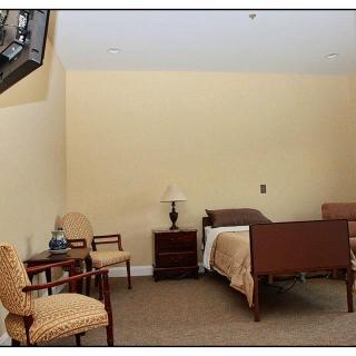 A simple bedroom with a single bed, chairs, and a lamp.