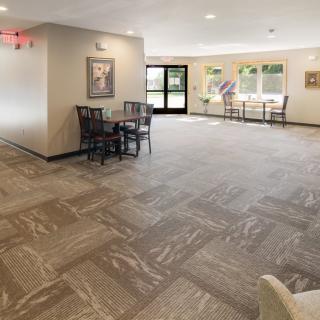 A spacious and well-lit lobby area with tables and chairs, featuring modern flooring and large windows.