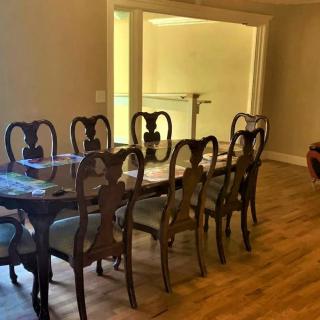 A spacious dining room with a wooden table and chairs on a wooden floor.