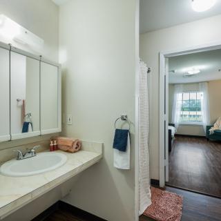 A modern bathroom with a view into a connected bedroom.