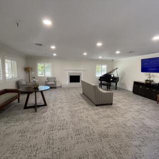 A spacious modern living room with a piano and a large television.