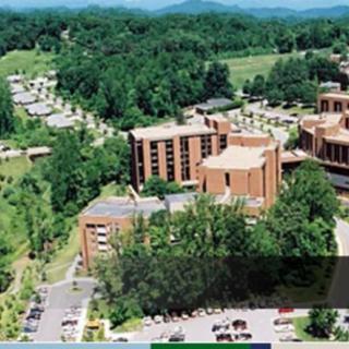 Aerial view of a campus surrounded by lush greenery and multiple buildings.