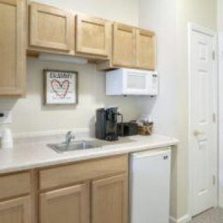 A compact kitchen area with wooden cabinets, a microwave, coffee maker, and mini fridge.