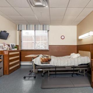 A hospital room with a single bed, television, and window.