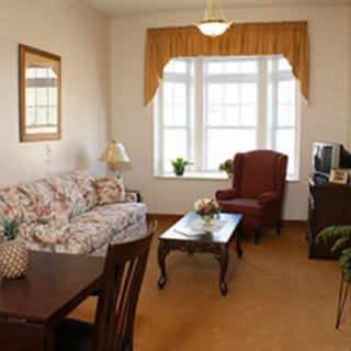 A cozy living room with a floral sofa, red armchair, and wooden furniture.