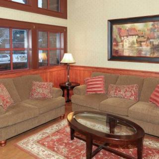 A cozy living room with brown sofas, a glass coffee table, and a patterned rug.