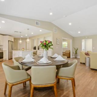 A modern open-concept dining area with a round table, elegant chairs, and a view of the kitchen and living room.