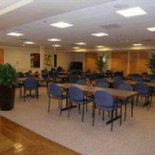A spacious indoor conference room equipped with multiple tables and chairs, ideal for meetings or group activities.