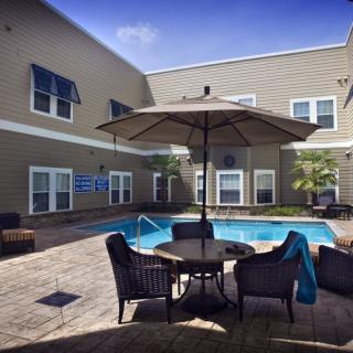 A cozy outdoor patio with a swimming pool, surrounded by comfortable seating and an umbrella.