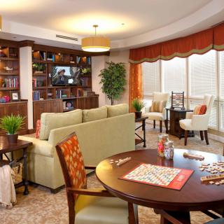 A cozy living room featuring elegant furniture, a well-stocked bookshelf, and a game table setup.