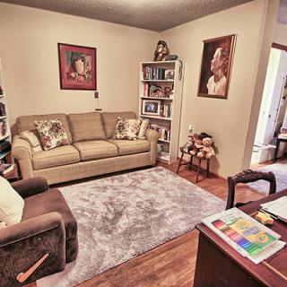 Cozy living room with a sofa, bookshelves, and artwork on the walls.