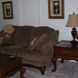 A cozy living room with a plush sofa, decorative pillows, an elegant lamp on an end table, and framed artwork.