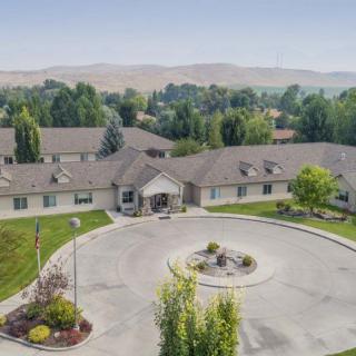 Aerial view of a large residential building with surrounding greenery and a circular driveway.