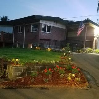 A brick house at dusk with a well-maintained garden and an American flag displayed.