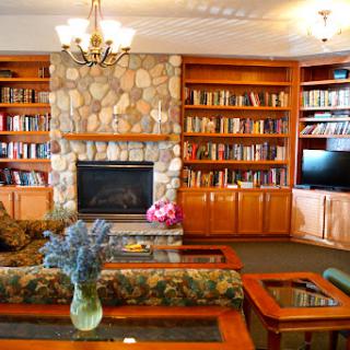 A cozy living room featuring a stone fireplace and extensive bookshelves filled with books.