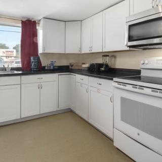 A modern kitchen with white cabinets and various appliances.