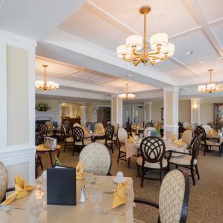 An elegant dining room with multiple tables and chandeliers.