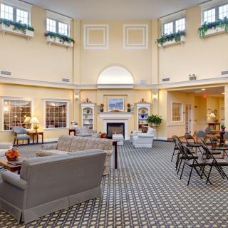 A spacious and elegant lounge featuring a central fireplace, comfortable seating, and large windows with natural light.