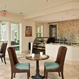 A cozy cafe interior with tables and chairs, featuring a display case and counter.