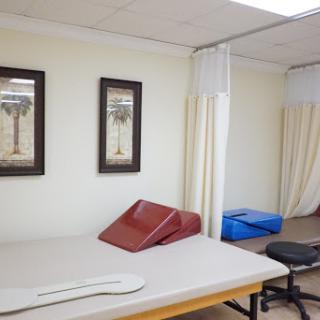 A well-equipped therapy room featuring treatment tables and privacy curtains.