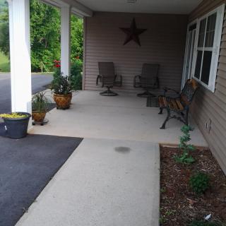 A cozy porch with chairs, benches, and decorative plants.