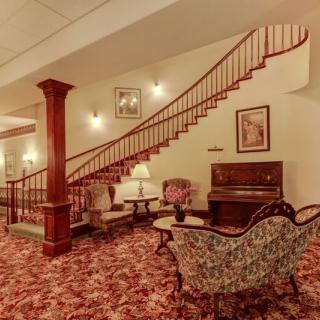 A vintage-style lounge area featuring a staircase, upholstered furniture, and a piano.