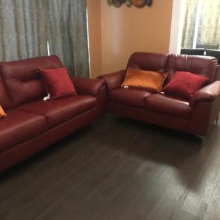 A cozy living room setup featuring two red sofas with decorative pillows on a wooden floor.